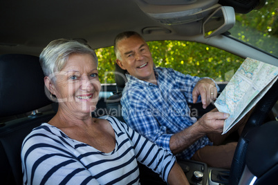 Senior couple with road map in car