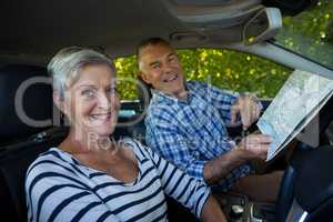 Senior couple with road map in car