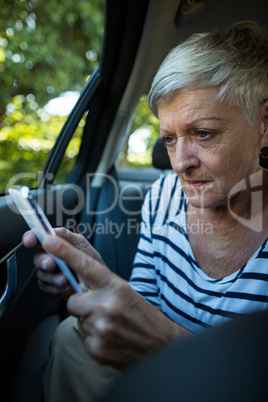 Senior woman using mobile phone in car