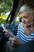 Senior woman using mobile phone in car