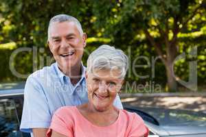 Smiling senior couple enjoying by car