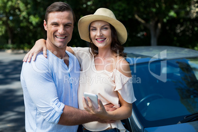 Happy young couple standing by car