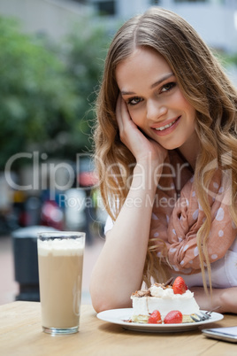 Portrait of smiling woman sitting by food at table