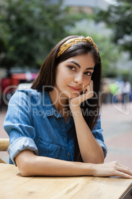 Thoughtful woman sitting at table in sidewalk cafe