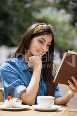 Smiling woman reading book while sitting on chair