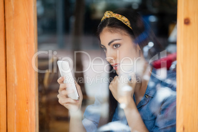 Thoughtful woman holding smart phone