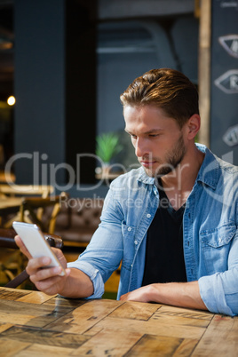 Man using mobile phone while sitting at table
