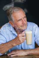 Senior thoughtful man looking away while holding cold coffee