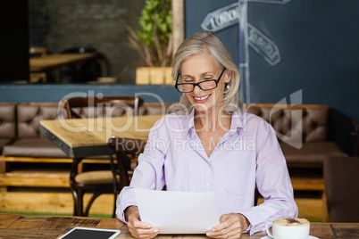 Smiling senior womanb holding tablet computer while sitting at table