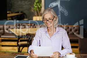 Smiling senior womanb holding tablet computer while sitting at table