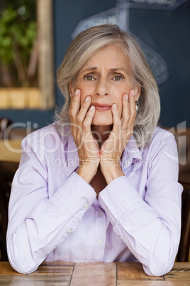 Portrait of worried senior woman sitting at table