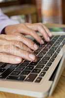 Close up of senior woman typing on laptop