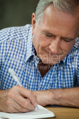 Close up of senior man writing on diary