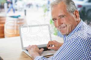 Portrait of smiling senior man using digital laptop