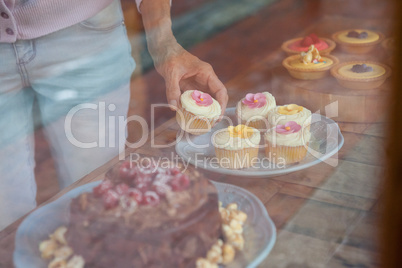 Midsection of woman holding cupcake while standing at table