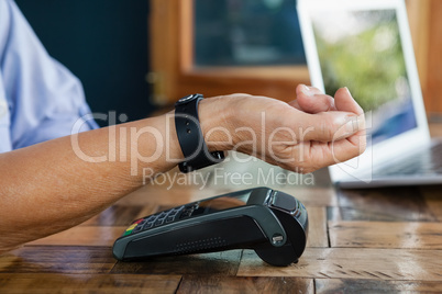 Close up of woman scanning smart watch on credit card reader