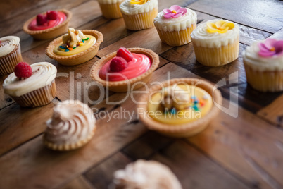 High angle view of tart and cupcakes arranged on table