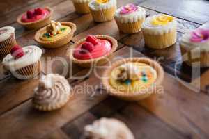 High angle view of tart and cupcakes arranged on table