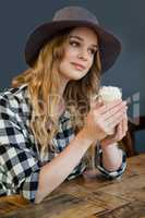 Young woman looking away while holding cold coffee
