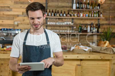 Waiter using digital tablet at counter