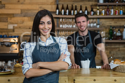 Portrait of smiling waitress and waiter standing at counter