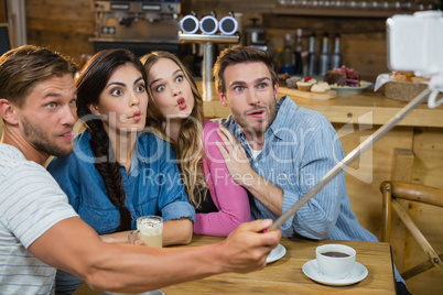 Happy friends taking selfie on mobile phone while having coffee