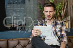 Young man using digital tablet while relaxing on sofa