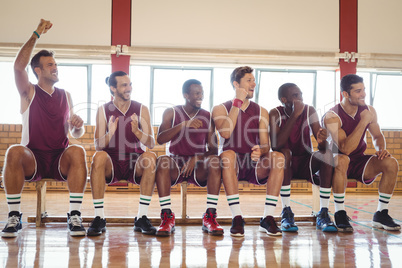 Excited basketball player sitting on bench
