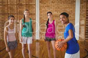 Portrait of smiling high school kids standing with basketball