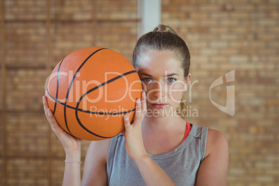 High school girl standing with basketball in the court