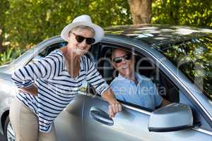 Senior woman leaning while man sitting in car