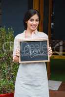 Portrait of waitress holding open signboard at the entrance
