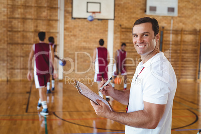 Basketball coach holding clipboard in the court