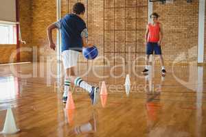 High school boys practicing football using cones for dribbling drill