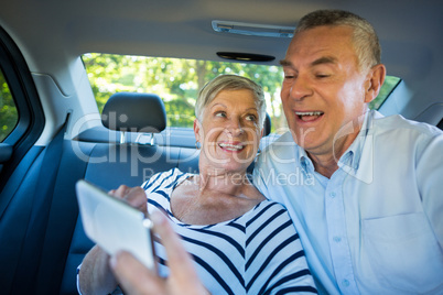 Senior couple using mobile phone in car