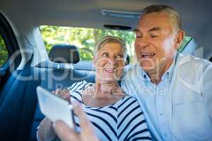 Senior couple using mobile phone in car