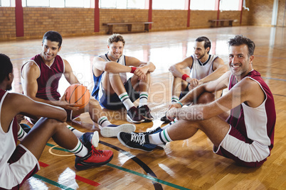 Basketball players interacting while relaxing in the court
