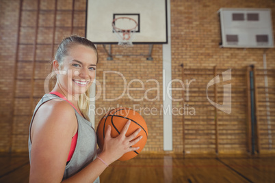 High school girl standing with basketball in the court