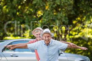 Carefree senior couple enjoying by car