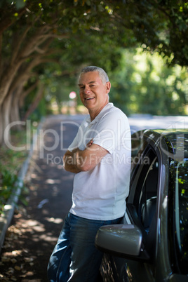 Smiling senior man standing by car