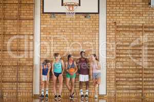 High school kids talking while leaning against the wall in basketball court