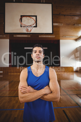 Male basketball player standing with his arms crossed