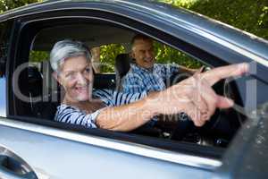Senior woman pointing away with man in car