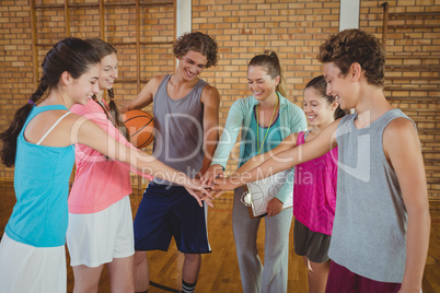 Female coach and high school kids with their hands stacked