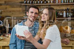 Portrait of smiling couple using digital tablet at counter