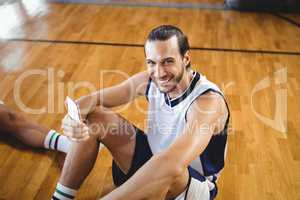 Portrait of smiling basketball player using mobile while relaxing