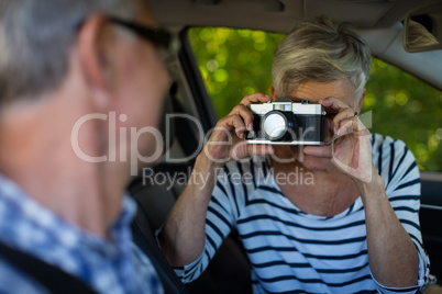 Woman photographing man in car