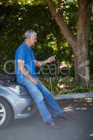 Man looking at mobile phone after car breakdown