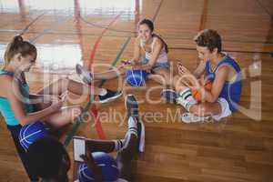 High school team using mobile phone while relaxing in the basketball court