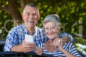 Happy senior couple leaning on car door